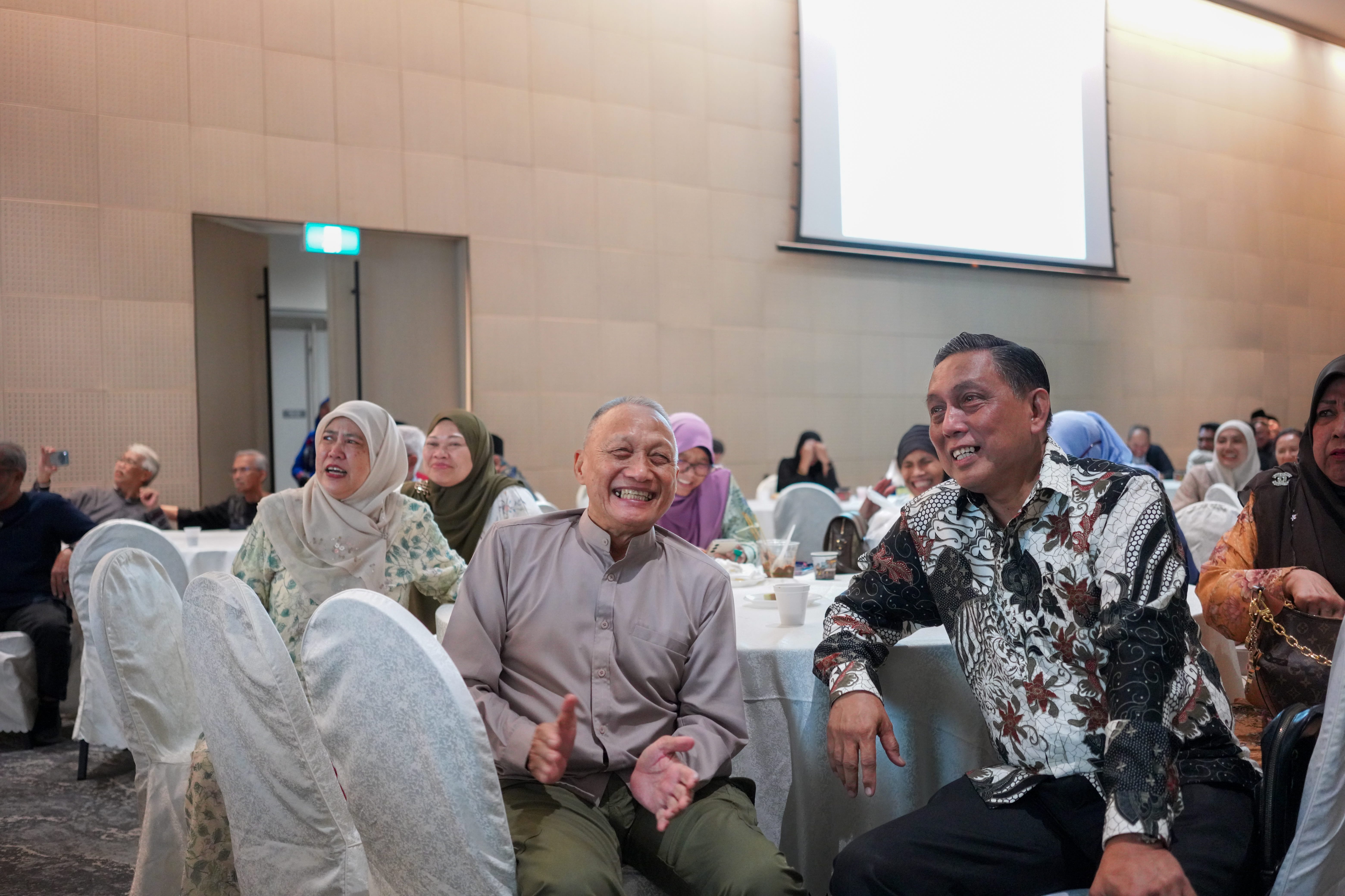 Guests seated at a banquet table smiling and laughing while watching the entertainment programme.